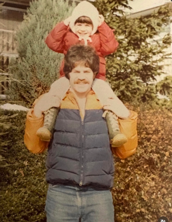 The founder as a young child riding on her father's shoulders